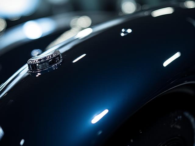 完璧に磨き上げられた高級車のボンネットに照明が反射する様子
